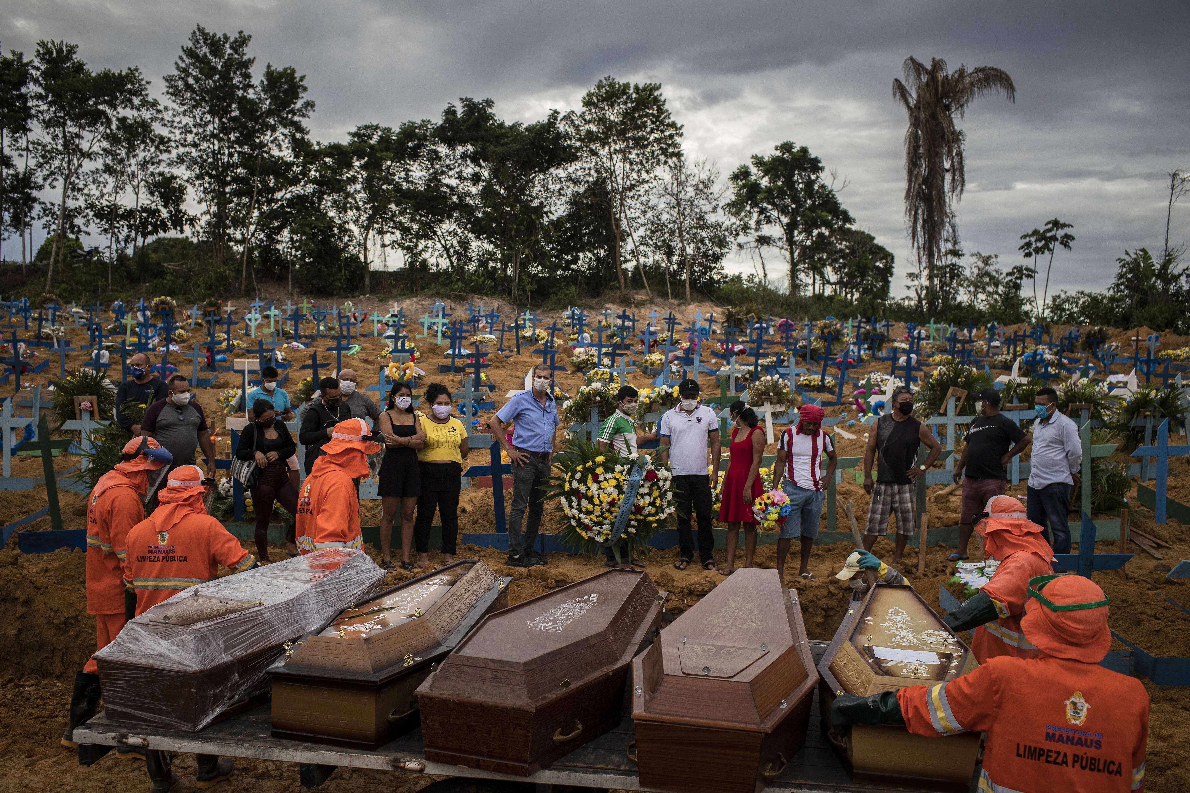 أشخاص يحضرون جنازة بسبب فيروس كورونا في مقبرة جماعية في مقبرة نوسا سينهورا أباريسيدا في ماناوس ، البرازيل.