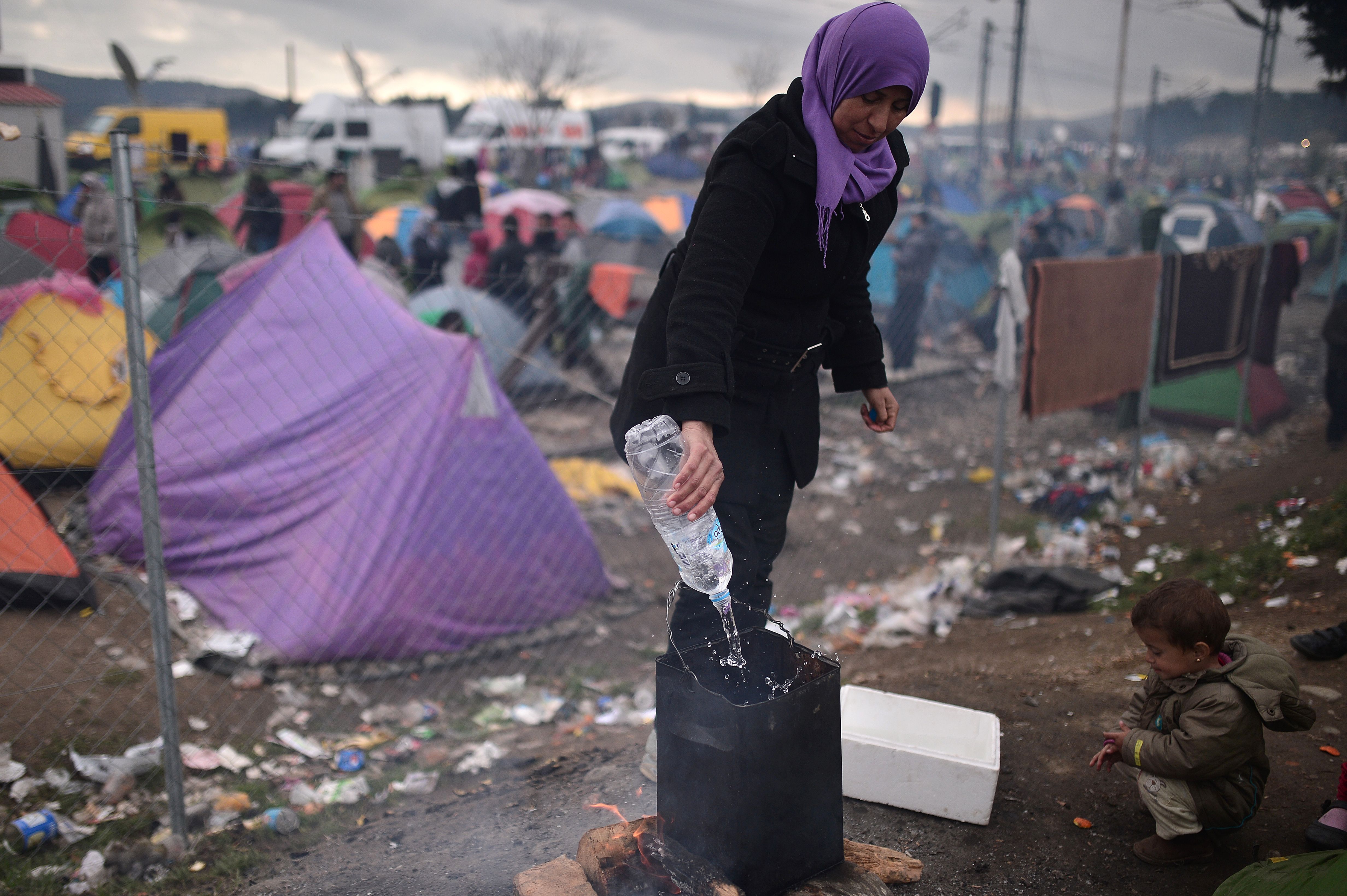 امرأة تغلي الماء في مخيم مؤقت على الحدود اليونانية المقدونية بالقرب من قرية إيدوميني.