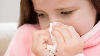 Girl blowing her nose --- Image by © Royalty-Free/Corbis